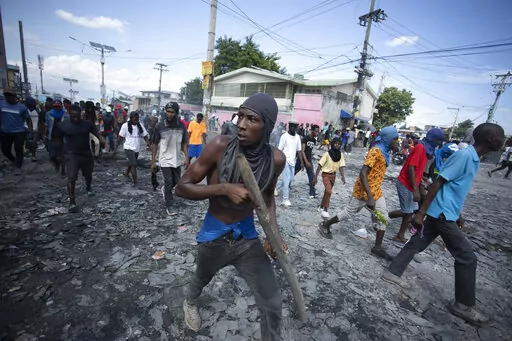 A protester carries a piece of wood simulating a weapon during a protest demanding the resignation of Prime Minister Ariel Henry, in the Petion-Ville area of Port-au-Prince, Haiti, Oct. 3, 2022. Haiti's government has agreed to request the help of international armed forces as gangs and protesters paralyze the country and basic supplies including fuel and water dwindle, a top ranking Haitian official told The Associated Press on Friday, Oct 7. (AP Photo/Odelyn Joseph, File)
