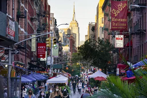 People walk through an area where restaurants operate outdoor spaces for dining that spread onto sidewalks and streets as part of continued COVID-19 economic impact mitigation efforts, Saturday, Oct. 3, 2020, in New York. As New York City forges ahead with its recovery, the pandemic is leaving lasting imprints, especially on city roadways: less room for cars and more space for people. (AP Photo/John Minchillo, File)