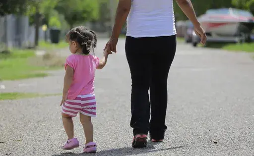 In this Sept. 16, 2015, photo, a woman in Sullivan City, Texas, who said she entered the country illegally, walks with her daughter who was born in the United States, but was denied a birth certificate. (AP Photo/Eric Gay, File)
