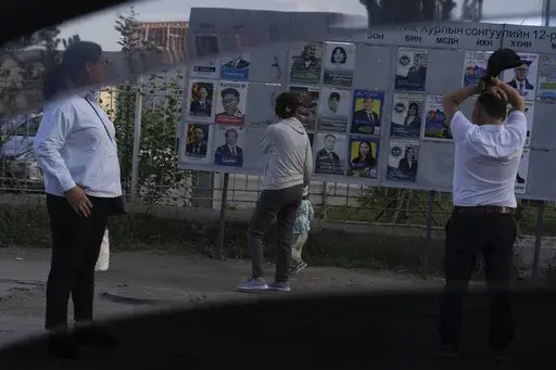 Residents look at candidates posters two days before polls open in Ulaanbaatar, Mongolia on June 26, 2024. Even in a busy year of elections, the next few days stand out. Voters go to the polls over the next week in fledgling democracies like Mauritania and Mongolia, in the Islamic Republic of Iran and in the stalwart democracies of Britain and France. (AP Photo/Ng Han Guan, File)