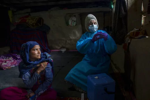 Masrat Farid, a healthcare worker, prepares to administer a dose of Covishield vaccine to Rubia Begum inside a hut during a COVID-19 vaccination drive in Gagangeer, northeast of Srinagar, Indian controlled Kashmir on June 22, 2021. Farid has traveled long distances to vaccinate mostly shepherds and nomadic herders in the remote meadows of the Himalayan region of Indian-controlled Kashmir. (AP Photo/Dar Yasin)