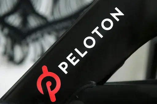 A Peloton logo is seen on the company's stationary bicycle on Nov. 19, 2019, in San Francisco. Peloton is laying off employees and raising prices for some of its equipment as part of its latest bid to make the business profitable and free up cash, according to a memo disclosed to employees on Friday, Aug. 12, 2022. (AP Photo/Jeff Chiu, File)