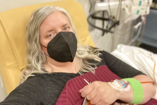 This photo provided by Amy Watson of Portland, Ore., shows her during an iron infusion in December 2022. Watson, approaching 50, says she has “never had any kind of recovery” from COVID-19. She has had severe migraines, plus digestive, nerve and foot problems. Recently she developed severe anemia. (Amy Watson via AP)