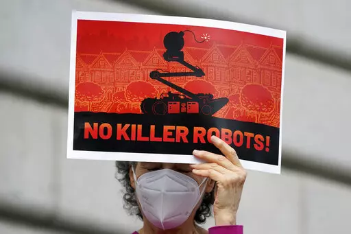 A woman holds up a sign while taking part in a demonstration about the use of robots by the San Francisco Police Department outside of City Hall in San Francisco, Monday, Dec. 5, 2022. The unabashedly liberal city of San Francisco became the unlikely proponent of weaponized police robots this week after supervisors approved limited use of the remote-controlled devices, addressing head-on an evolving technology that has become more widely available even if it is rarely deployed to confront suspec