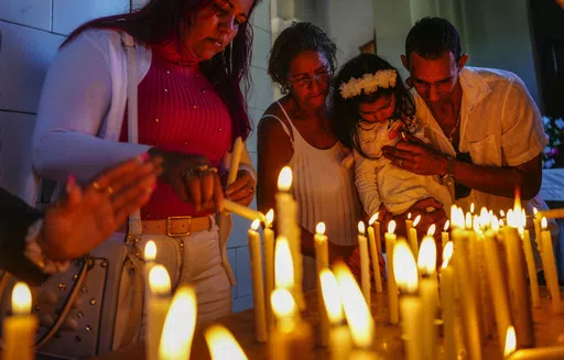 People light candles in honor of Cuba's patron saint, the Virgin of Charity of Cobre, at her shrine in El Cobre, Cuba, Feb. 11, 2024. The Vatican-recognized Virgin, venerated by Catholics and followers of Afro-Cuban Santeria traditions, is at the heart of Cuban identity. (AP Photo/Ramon Espinosa, File)