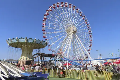 People ride the Giant Wheel and flying chair ride at Gillian's Wonderland, the popular amusement park on the boardwalk in Ocean City, N.J., during its final day of operation before shutting down for good, Sunday, Oct. 13, 2024. (AP Photo/Wayne Parry)
