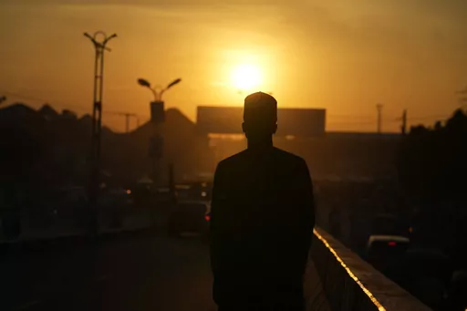 An atheist stands against the sunset sky in a street in Kano, Nigeria Friday, July 14, 2023. Nonbelievers in Nigeria said they perennially have been treated as second-class citizens in the deeply religious country whose 210 million population is almost evenly divided between Christians dominant in the south and Muslims who are the majority in the north. Some nonbelievers say threats and attacks have worsened in the north since the leader of the Humanist Association of Nigeria, Mubarak Bala, was 