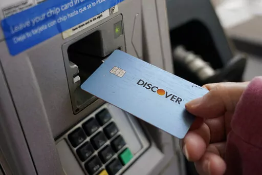 A consumer uses a Discover card in Madison, Miss., Thursday, July 1, 2021.  In 2021,  dedicate a financial account to goods, services and activities that bring you joy. Perhaps this fund would cover monthly massages or weekly smoothies, or it could be used to save up for a vacation.  (AP Photo/Rogelio V. Solis)