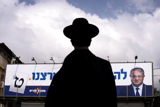 An ultra-Orthodox Jewish man walks by an election campaign billboard showing Itamar Ben-Gvir, Israeli far-right lawmaker and the head of "Jewish Power" party, in Bnei Brak, Israel Monday, Oct. 24, 2022. Israel is holding its fourth election in less than two years. Israel's most extremist politician, known for his inflammatory anti-Arab speeches and stunts, is attracting new supporters from a previously untapped demographic young ultra-Orthodox Jews, one of the fastest-growing segments of the cou