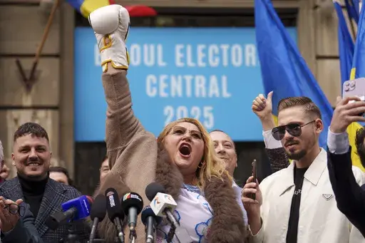 Controversial politician Diana Sosoaca, who was barred by a top court from entering last year's presidential election, raises her hands wearing boxing gloves and speaking outside the country's electoral authority after she registered an unlikely bid to enter the May rerun in Bucharest, Romania, Thursday, March 13, 2025. (AP Photo/Vadim Ghirda)