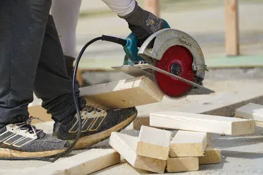 A workman cuts sections of a bean at a housing site in Madison County, Miss., Tuesday, March 16, 2021.  The busy season for home remodeling usually ends in late summer or early fall, but contractors say demand from the pandemic renovation rush hasn’t let up.  (AP Photo/Rogelio V. Solis)