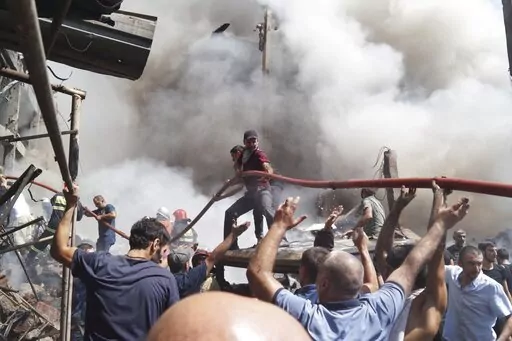 People help firefighters to deliver water to extinguish flames at Surmalu market about two kilometers (1.2 miles) south of the center Yerevan, Armenia, Sunday, Aug. 14, 2022. A strong explosion at a fireworks storage area has ripped through a market in Armenia's capital. At least one person has been killed and about 20 others have been injured. The blast on Sunday set off a large fire. (AP Photo/Daniel Bolshakov)