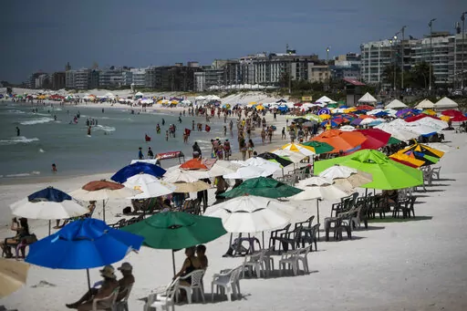 Beachgoers congregate on Fort Beach in Cabo Frio, Brazil, Wednesday, Dec. 15, 2021. G.A.S Consulting & Technology, a cryptocurrency investment firm founded by Glaidson Acacio dos Santos, a former waiter-turned-multimillionaire who is the central figure in what is alleged to be one of Brazil’s biggest-ever pyramid schemes, was based in the beach town dos Santos called home. (AP Photo/Bruna Prado)