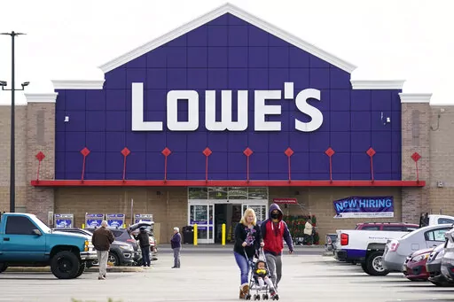Shoppers walk in the lot of a Lowe's home improvement store in Philadelphia, Wednesday, Nov. 17, 2021.   The home improvement company is teaming up with Petco to offer pet departments within its stores. The first Lowe’s with a Petco is expected to open in February 2022 in Alamo Ranch, Texas.   (AP Photo/Matt Rourke)