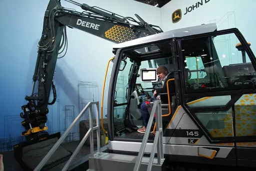 People look at a John Deere electric excavator at the John Deere booth during the CES tech show Friday, Jan. 6, 2023, in Las Vegas. (AP Photo/John Locher)