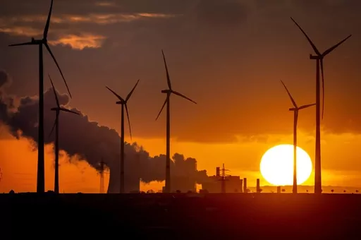 A coal-fired power plant operates near wind turbines Niederaussem, Germany, as the sun rises on Nov. 2, 2022. Climate negotiators gather in Dubai for marathon United Nations talks that include a first-ever assessment of how well the world is doing in its battle against global warming. (AP Photo/Michael Probst, File)