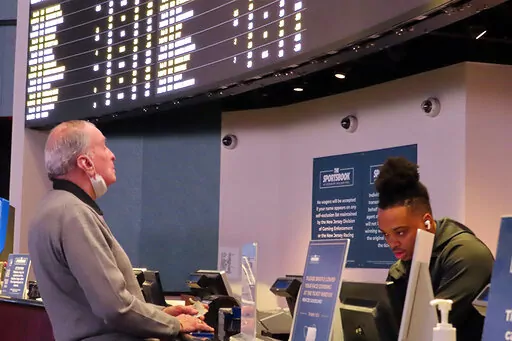 A man places a bet at the sportsbook at the Ocean Casino Resort, on Thursday, Feb. 10, 2022, in Atlantic City, N.J. The American Gaming Association estimates more than 31 million Americans will bet on this year's Super Bowl NFL football game. (AP Photo/Wayne Parry)