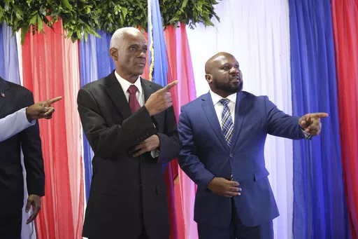 Edgard Leblanc Fils, left, and Smith Augustin prepare to pose for a group photo with the transitional council after it named Fils as its president in Port-au-Prince, Haiti, Tuesday, April 30, 2024. The transitional council will act as the country’s presidency until it can arrange presidential elections sometime before it disbands, which must be by February 2026. (AP Photo/Odelyn Joseph)