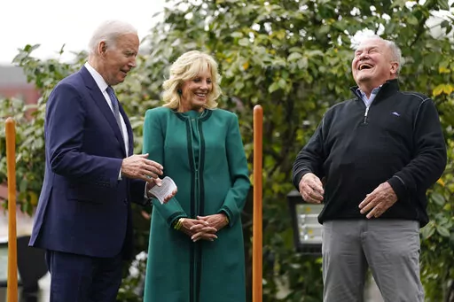 Dale Haney, the chief White House groundskeeper, right, laughs as he stands with President Joe Biden and first lady Jill Biden during a tree planting ceremony on the South Lawn of the White House, Monday, Oct. 24, 2022, in Washington. As of this month, Haney has tended the lawns and gardens of the White House for 50 years. (AP Photo/Evan Vucci)