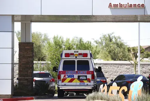 In this June 10, 2020, file photo, an ambulance is parked at Arizona General Hospital in Laveen, Ariz. Arizona is continuing to see slight downward trends with coronavirus hospitalizations as officials find more related deaths. Arizona is committing millions of dollars and asking the federal government for extra help as hospitals face a growing strain from rising COVID-19 caseloads and warn they are nearing their limits. (AP Photo/Ross D. Franklin, File)