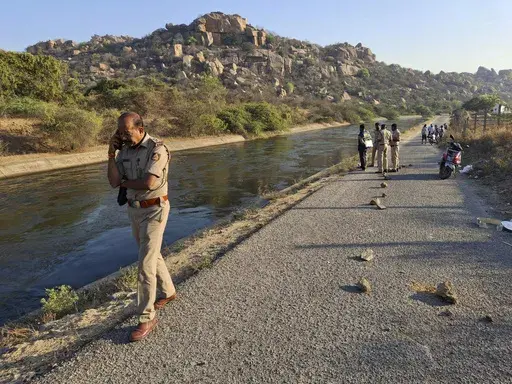 A police officer speaks on his mobile phone at the scene as they search for the male travelers who were pushed into the canal by three men accused of gang-raping two women, in Koppal district of southern state of Karnataka, India, Friday, March 7, 2025. (AP Photo)
