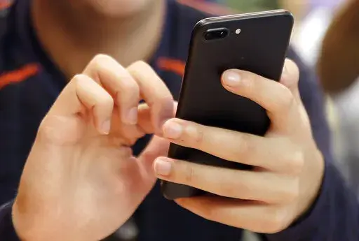 In this Sept. 16, 2017, file photo, a person uses a smart phone in Chicago. The next time you check your DMs, you could see a message from a debt collector. Late last year, the Consumer Financial Protection Bureau rolled out new rules that allow debt collectors to contact debtors through social media. (AP Photo, File)
