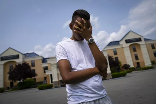 Mohamed, a 19-year-old fleeing political persecution in the northwest African country of Mauritania, poses for a photo that obscures his face to protect his identity, outside the Crossroads Hotel, before heading into town for a work opportunity, Monday, May 22, 2023, in Newburgh, N.Y. Mohamed is one of about 400 international migrants the city has been putting up in a small number of hotels in other parts of the state this month to relieve pressure on its overtaxed homeless shelter system. (AP P