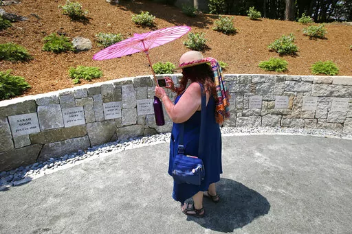 Karla Hailer, a fifth-grade teacher from Scituate, Mass., takes a video on July 19, 2017, where a memorial stands at the site in Salem, Mass., where five women were hanged as witches more than three centuries years earlier. Massachusetts lawmakers on Thursday, May 26, 2022, formally exonerated Elizabeth Johnson Jr., clearing her name 329 years after she was convicted of witchcraft in 1693 at the height of the Salem Witch Trials. (AP Photo/Stephan Savoia, File)