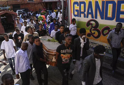 Friends and family accompany the coffin that contain the remains of Jhon-Roselet Joseph, killed by a stray bullet during clashes between police, and gang members who were trying to invade the Solino neighborhood, during a funeral procession in Port-au-Prince, Haiti, Saturday, May 18, 2024 (AP Photo/Ramon Espinosa)