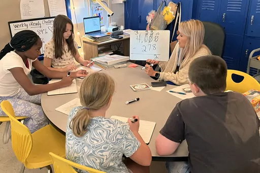 Piedmont Elementary School math teacher Cassie Holbrooks helps a small group of fourth-grade students with a three-digit subtraction problem in Piedmont, Ala., on Thursday, Aug. 31, 2023. Piedmont, a 1,100-student district where seven out of 10 qualify for free or reduced-prince lunch, has stuck with an approach it began before the pandemic: It gave teachers more time to dig into data on student performance and increased instructional time for math teachers to focus on specific skills. (Trisha P