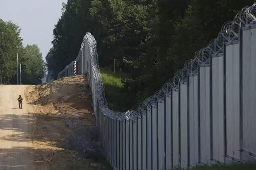 A Polish border guard patrols the area of a newly built metal wall on the border between Poland and Belarus, near Kuznice, Poland, Thursday, June 30, 2022. A year after migrants started crossing into the European Union from Belarus to Poland, Polish Prime Minister Mateusz Morawiecki and top security officials visited the border area on Thursday to mark the completion of a new steel wall. (AP Photo/Michal Dyjuk)