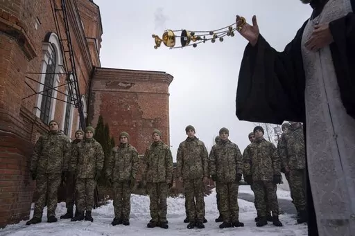 An Orthodox priest blesses Ukrainian Military Air Force University cadets after a monthly memorial service for soldiers who were killed during the fighting against Russia-backed separatists in eastern Ukraine, in Kharkiv, Ukraine, Thursday, Feb. 3, 2022. Russia maintains it has no intention to attack its neighbor, but demands that NATO won't expand to Ukraine and other ex-Soviet nations or deploy weapons there. It also wants the alliance to roll back its deployments to Eastern Europe. (AP Photo/
