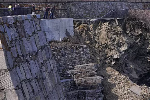 City officials and a private engineering group representatives peer down at debris of a collapsed section of the historic Cliff Walk, March 15, 2022, in Newport, R.I. Gov. Dan McKee issued a disaster declaration on Tuesday, June 13, 2023, that will allow the state Department of Transportation to apply for $10 million in emergency relief funds from the Federal Highway Administration. (AP Photo/Charles Krupa, File)