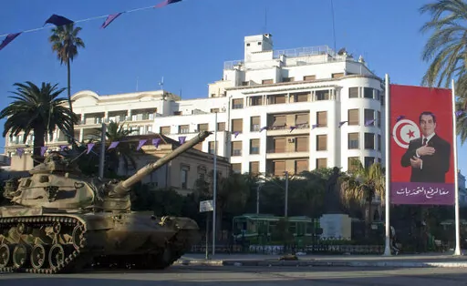 A tank is seen next to the portrait of former Tunisian President Zine El Abidine Ben Ali, on a street in Tunis, Saturday, Jan. 15, 2011. Despite an election debacle, Tunisia's increasingly authoritarian president appears determined to upend the country's political system, threatening to unravel the fragile democracy and collapse the economy in the North African nation that a decade ago stood out as a model of good governance and economic prosperity in the aftermath of the Arab Spring protests. (