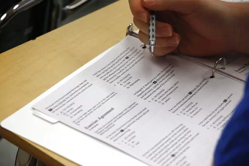 In this photo taken Jan. 17, 2016, a student looks at questions during a college test preparation class at Holton Arms School in Bethesda, Md.  The SAT exam will move from paper and pencil to a digital format, administrators announced Tuesday, Jan. 25, 2022, saying the shift will boost its relevancy as more colleges make standardized tests optional for admission.   (AP Photo/Alex Brandon)