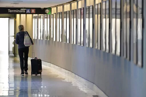 A traveler pulls their luggage between terminals at Logan International Airport, Wednesday, Jan. 11, 2023, in Boston. Airline and hotel elite status extensions due to the COVID-19 pandemic are expiring this year, and the companies are raising the requirements to earn status. (AP Photo/Steven Senne, File)