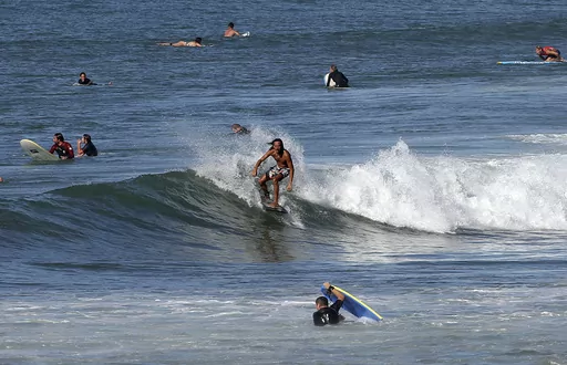 A surfer rides a wave in the Atlantic Ocean in Biarritz, southwestern France, Oct. 7, 2023. October was the fifth straight month that Earth set a record for the hottest month in recorded history. (AP Photo/Bob Edme, File)