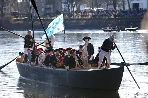 FILE - John Godzieba, as Gen. George Washington, second right, stands in a boat during a re-enactment of Washington's daring Christmas 1776 crossing of the Delaware River in Washington Crossing, Pa., on Dec. 25, 2016.  Spectators were once again being invited to gather along the Delaware River to watch an annual reenactment of George Washington’s crossing of the Delaware River on Christmas Day, Saturday, Dec. 25, 2021,  a year after an online re-enactment was posted instead. (AP Photo/Mel Evan
