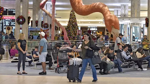 Holiday travelers pass by "Phoebe" the Flamingo at the Tampa International Airport, Friday, Dec. 22, 2023, in Tampa, Fla. Conditions were mostly nice for travelers flying ahead of and on Christmas Day this year, but some naughty disruptions plagued those flying with Southwest Airlines again this year. By midday Monday, Dec. 25, only 138 flights within, into or out of the U.S. had been canceled and 1,366 were delayed, according to FlightAware, a tracking website. (AP Photo/Chris O'Meara, File)