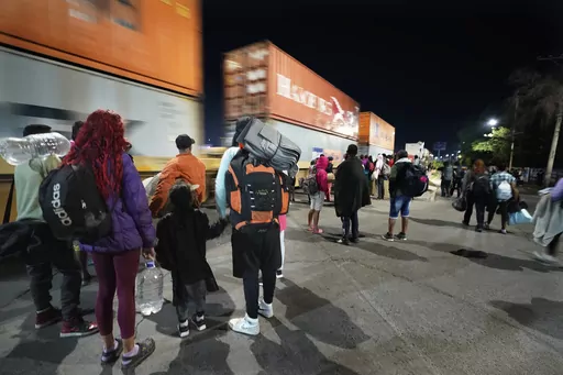 Migrants watch a freight train pass as they wait for a northbound freight train that stops long enough for them to hop, in Irapuato, Mexico, Saturday, Sept. 23, 2023. (AP Photo/Marco Ugarte)