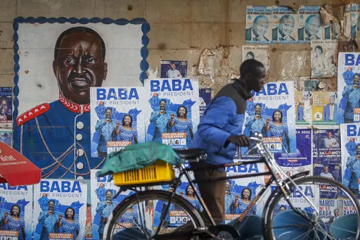 A man pushes a bicycle past campaign posters for Kenyan presidential candidate Raila Odinga, referred to affectionately as "Baba", the Swahili word for "father", and his running mate Martha Karua, in the low-income Kibera neighborhood of Nairobi, Kenya Friday, July 29, 2022. Kenya's Aug. 9 election is ripping open the scars of inequality and corruption as East Africa's economic hub chooses a successor to President Uhuru Kenyatta. (AP Photo/Brian Inganga)