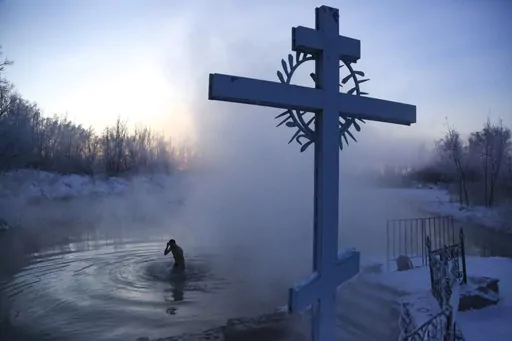 A man crosses himself while bathing in the water during a traditional Epiphany celebration as the temperature dropped to about -24 degrees (-11,2 degrees Fahrenheit) near the Achairsky monastery outside Siberian city of Omsk, Russia, Tuesday, Jan. 19, 2021. Water that is blessed by a cleric on Epiphany is considered holy and pure until next year's celebration, and is believed to have special powers of protection and healing. The Russian Orthodox Church follows the old Julian calendar.. (AP Photo