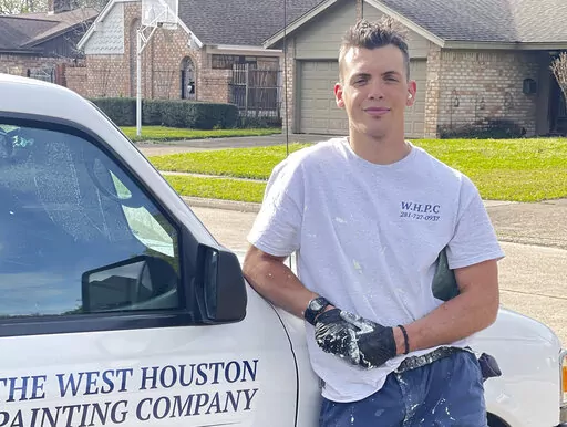 Anthony Giusti stands outside a home he is painting in Houston on March 23, 2022. The San Francisco-area native left the Bay Area last year and moved to Houston where he started a home-painting business. He was one of tens of thousands of people who left the biggest metro areas in the U.S. and moved to Sunbelt metros during the first full year of the pandemic, according to U.S. Census Bureau data released Thursday, March 24.  (Garima Vyas via AP)