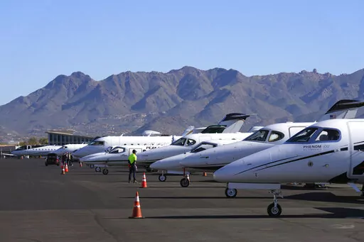 A Scottsdale Airport staffer waits on a private jet, as the airport gears up for the expected dramactic increase in private jet traffic, leading up to the NFL Super Bowl LVII football game at Scottsdale Airport in Scottsdale, Ariz., Thursday, Feb. 2, 2023. (AP Photo/Ross D. Franklin)