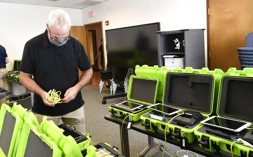 Mark Splonskowski assembles electronic poll book kits that voters will uses to sign in at polling locations at the Albany County Board of Elections building, Oct. 14, 2020, in Albany, N.Y. Attempts to develop the first-ever national standards for electronic voter rolls, the source of problems and hacking concerns in previous elections, may not be ready or available for wide use in time for the 2024 presidential election, concerning election experts. (AP Photo/Hans Pennink, File)