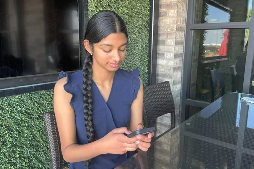 Shreya Nallamothu looks at her phone in Bloomington, Ill., on Tuesday, May 9, 2023. Illinois lawmakers aim to make their state what they say will be the first in the country to create protections for child social media influencers. Nallamothu, 15, raised her concerns to Illinois state Sen. David Koehler of Peoria, who then set the legislation in motion. (AP Photo/Claire Savage)