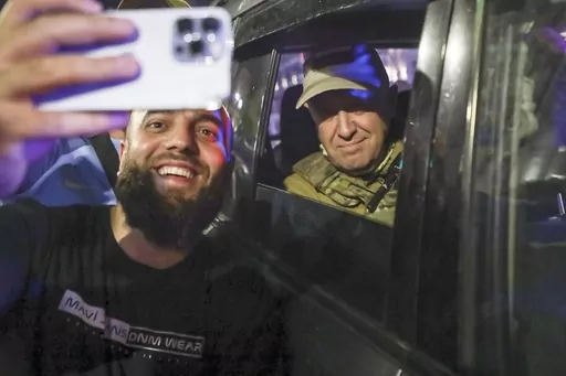 Yevgeny Prigozhin, the owner of the Wagner Group military company, right, sits inside a military vehicle posing for a selfie photo with a local civilian on a street in Rostov-on-Don, Russia, Saturday, June 24, 2023, prior to leaving an area of the headquarters of the Southern Military District. Kremlin spokesman Dmitry Peskov said that Prigozhin's troops who joined him in the uprising will not face prosecution and those who did not will be offered contracts by the Defense Ministry. After the dea