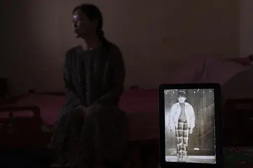 Yooree Kim sits for a portrait with a computer tablet displaying a picture of her taken before she was sent from South Korea to be adopted by a family in France when she was 11 years old, in her apartment in Seoul, South Korea, Sunday, May 19, 2024. (AP Photo/Jae C. Hong)