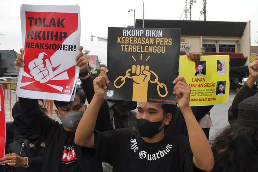 Activists hold up posters during a rally against Indonesia's new criminal law in Yogyakarta, Indonesia, Tuesday, Dec. 6, 2022. The country's parliament passed the long-awaited and controversial revision of its penal code Tuesday that criminalizes extramarital sex for citizens and visiting foreigners alike. Writings on the posters read "Reject the revised penal code" and "Revised criminal law shackles press freedom." (AP Photo/Slamet Riyadi)