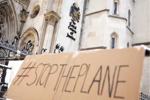 A placard left outside the High Court where the ruling on Rwanda deportation flights is taking place, in London Monday, June 13, 2022. British Foreign Secretary Liz Truss says the first deportation flight to Rwanda will take off in the evening, Tuesday, June 14, 2022, regardless of how many people are on board, as immigration attorneys launch case-by-case appeals on behalf of the migrants scheduled for removal. The comments comes a day after two British courts refused to block the deportation fl